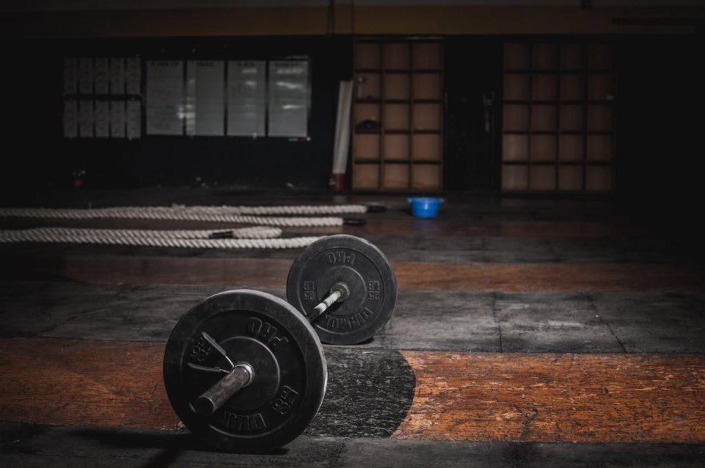 pexels-photo-1552252 A lone barbell rests in an empty, dimly lit gym, emphasizing strength and solitude.
